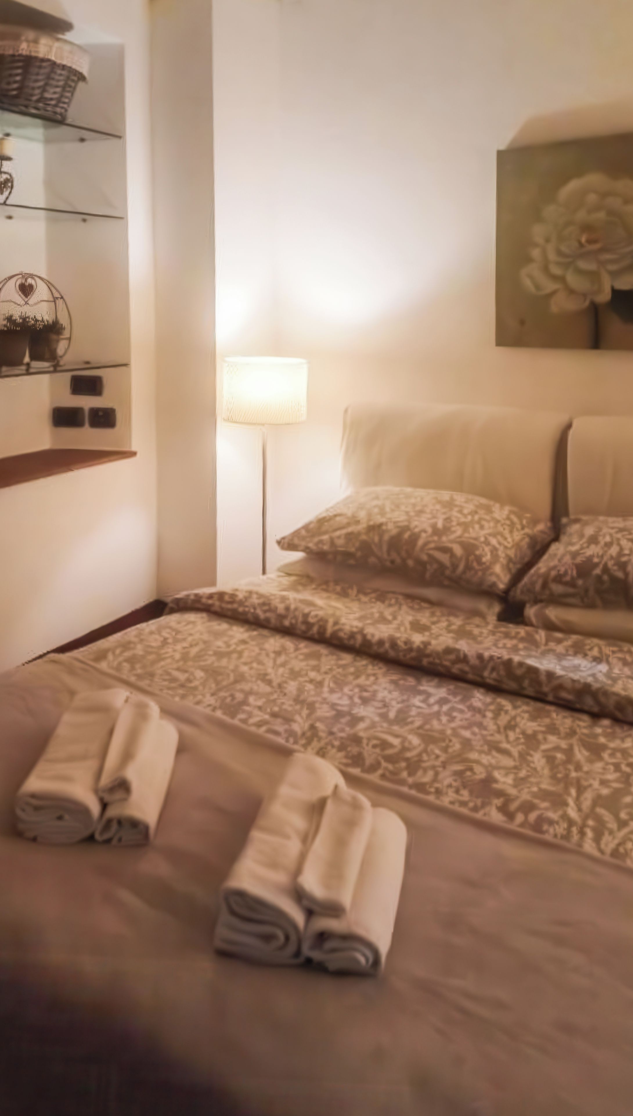 Une chambre d’hôtel avec un lit, des oreillers, une lampe, un tableau et des serviettes pliées posées sur le lit.