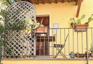 A balcony with a metal railing, potted plants, and a wooden door. - Il Grillo (Rosignano Marittimo)