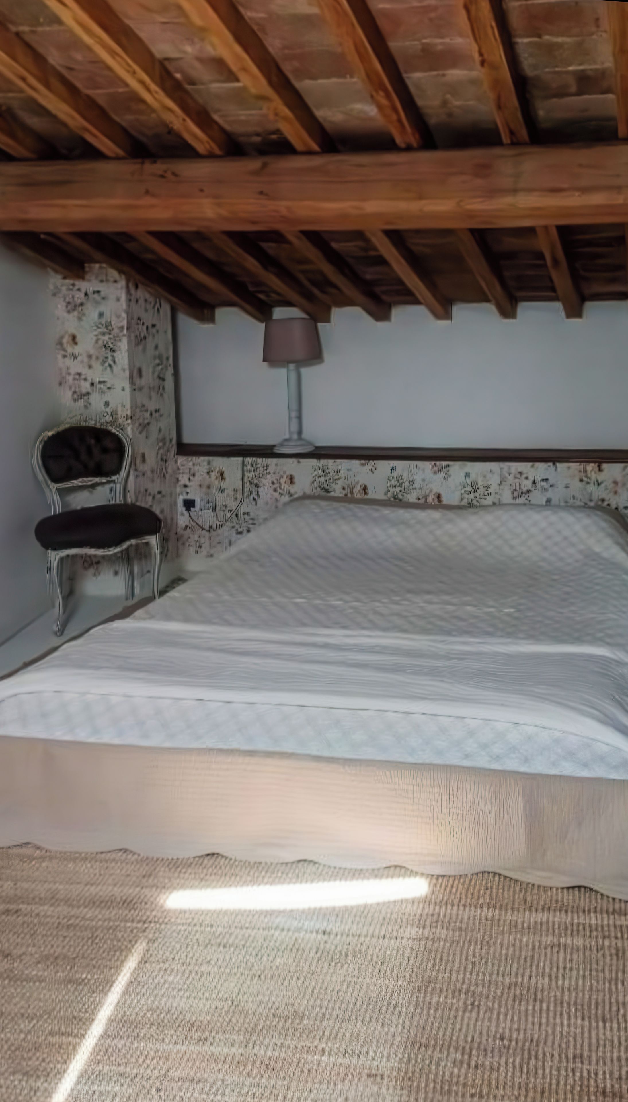 Une chambre à coucher avec un lit, une chaise et une lampe.