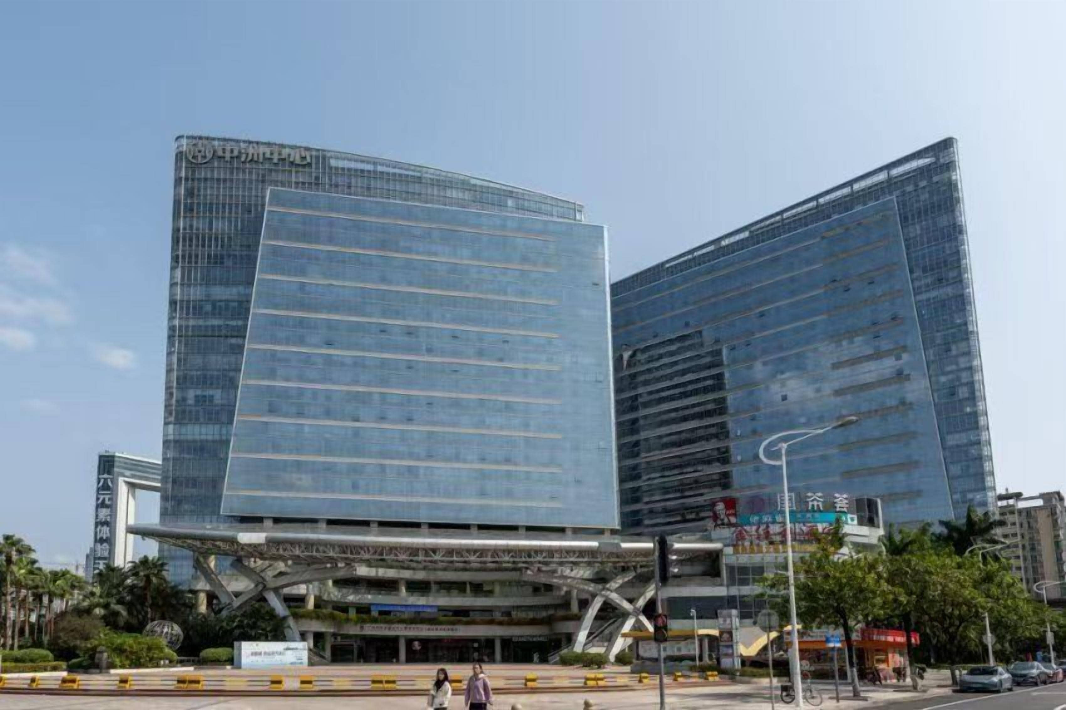 Een modern gebouw met een glazen gevel en een opvallende, gebogen structuur aan de basis.
