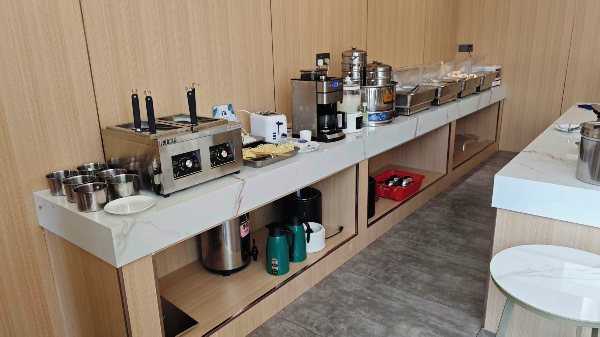 Een keuken met een kookplaat, koffiezetapparaat en diverse keukengerei.
