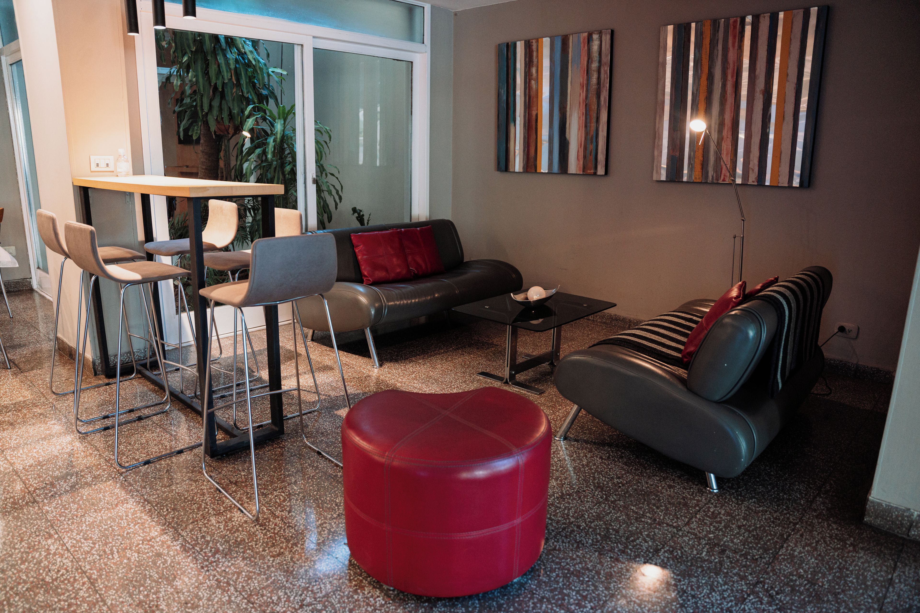 Una sala de estar moderna con un sofá, un reposapiés y sillones. Hay una mesa de comedor con sillas, una mesa de centro y obras de arte en las paredes.