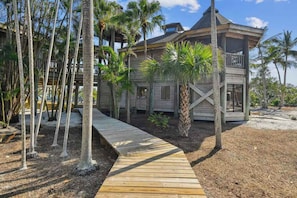 A wooden house with a deck, surrounded by palm trees. - Private Island Oasis | Pool + Dock • Boat-In Only (Longboat Key)