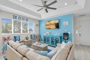 A living room with a sofa, a coffee table, a TV, and a ceiling fan. - Coral Tides - Waterfront Escape with 40' Dock (Marathon)