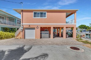 A two-story building with a garage, a covered outdoor area, and a balcony. - Coral Tides - Waterfront Escape with 40' Dock (Marathon)