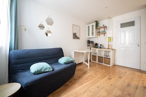 A modern living room with a dark blue sofa, two light blue cushions, a small white table, and a wooden floor. - L’Écrin d’Ax - 500 mètres des télécabines (Ax-les-Thermes)