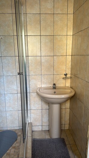 A bathroom with a shower, a sink, and a tiled floor. - Charming humble cottage Johannesburg 4 min from Eastgate and very peaceful (Johannesburg)