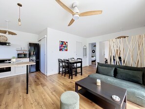 A modern living space with a dining area, kitchen, and a sofa. - Les Caraïbes Bretons - 500m de la plage (Saint-Pabu)