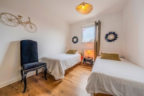 A room with two single beds, a chair, a bicycle decoration, and a window with a view. - Les Caraïbes Bretons - 500m de la plage (Saint-Pabu)