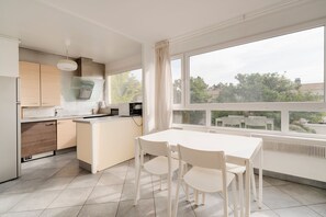 Eine moderne Küche mit Essbereich, großen Fenstern und Blick ins Freie.