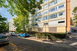 Ein mehrgeschossiges Wohngebäude mit Parkplatz davor.