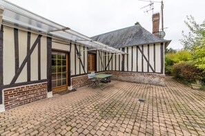 A traditional half-timbered house with a brick patio and a table. - Le Cottage de Saint Cyr - Maison avec grand jardin (Saint-Pierre-de-Salerne)