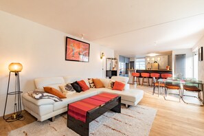 Ein modernes Wohnzimmer mit einer Couch, einem Couchtisch und einem Essbereich mit Barhocker.