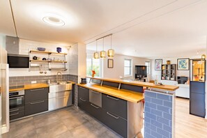A modern kitchen with a central island, stainless steel appliances, and a built-in oven. - My Babylone - Climatisé avec parking privé (Toulouse)