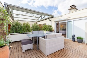 A covered patio area with a table and chairs, surrounded by greenery and a view of the sky. - My Babylone - Climatisé avec parking privé (Toulouse)