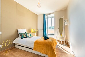 A modern bedroom with a bed, a window with curtains, a floor lamp, and a radiator. - My Babylone - Climatisé avec parking privé (Toulouse)