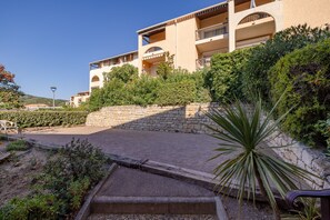 A multi-story hotel with balconies, surrounded by greenery and a stone retaining wall. - Launa - 2 min à pied de la mer (Roquebrune-sur-Argens)