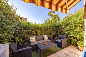 Un espace extérieur aménagé avec des meubles en osier et un auvent à rayures.