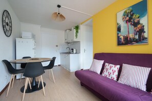 A compact living space with a dining area, kitchenette, and a sofa with patterned cushions. - Le Cocon du Cap d'Agde - 5 min du port (Agde)