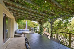 An outdoor patio with a table and chairs, a sofa, and a pergola covered with climbing plants. - La Maison du Logeo - A 300 m du Golfe (Sarzeau)