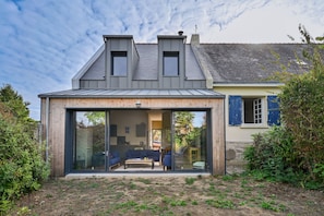 A modern house with a glass-enclosed patio, a dining area, and a visible kitchen. - La Maison du Logeo - A 300 m du Golfe (Sarzeau)