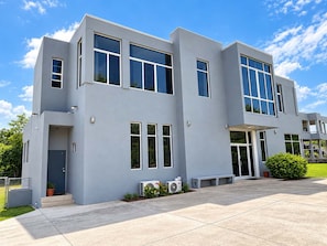 A modern two-story building with large windows, a flat roof, and a concrete patio. - New 2BR - 2BA Apartment at San Ignacio, Cayo (San Ignacio)
