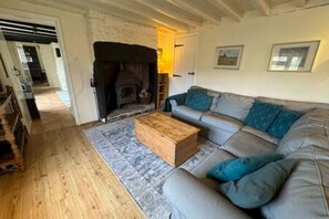 A living room with a fireplace, a sofa, and a coffee table. - Toast Stays - Woodbine Cottage (Alston Moor)