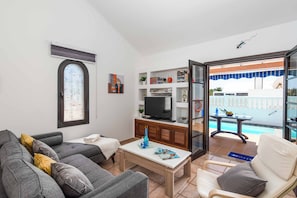 Ein Wohnzimmer mit Sofa, Couchtisch, Fernseher und Bücherregal.