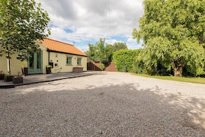 A house with a gravel driveway, a green door, and a tiled roof. - Toast Stays - East Farm Cottage (Thinford)