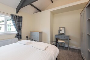 A bedroom with a bed, a dresser, a chair, and a wardrobe. - Toast Stays - East Farm Cottage (Thinford)