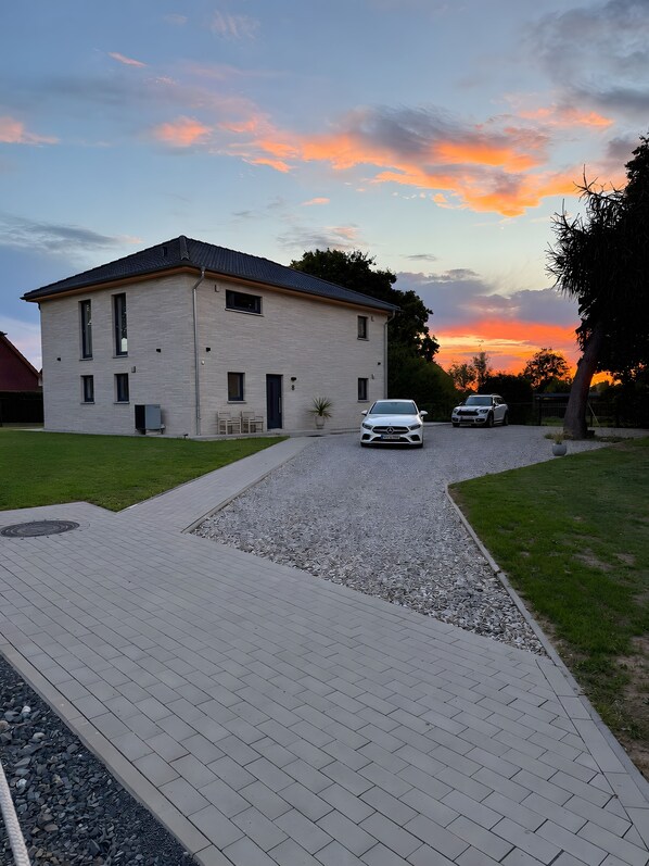 A two-story building with a paved driveway and a gravel area.