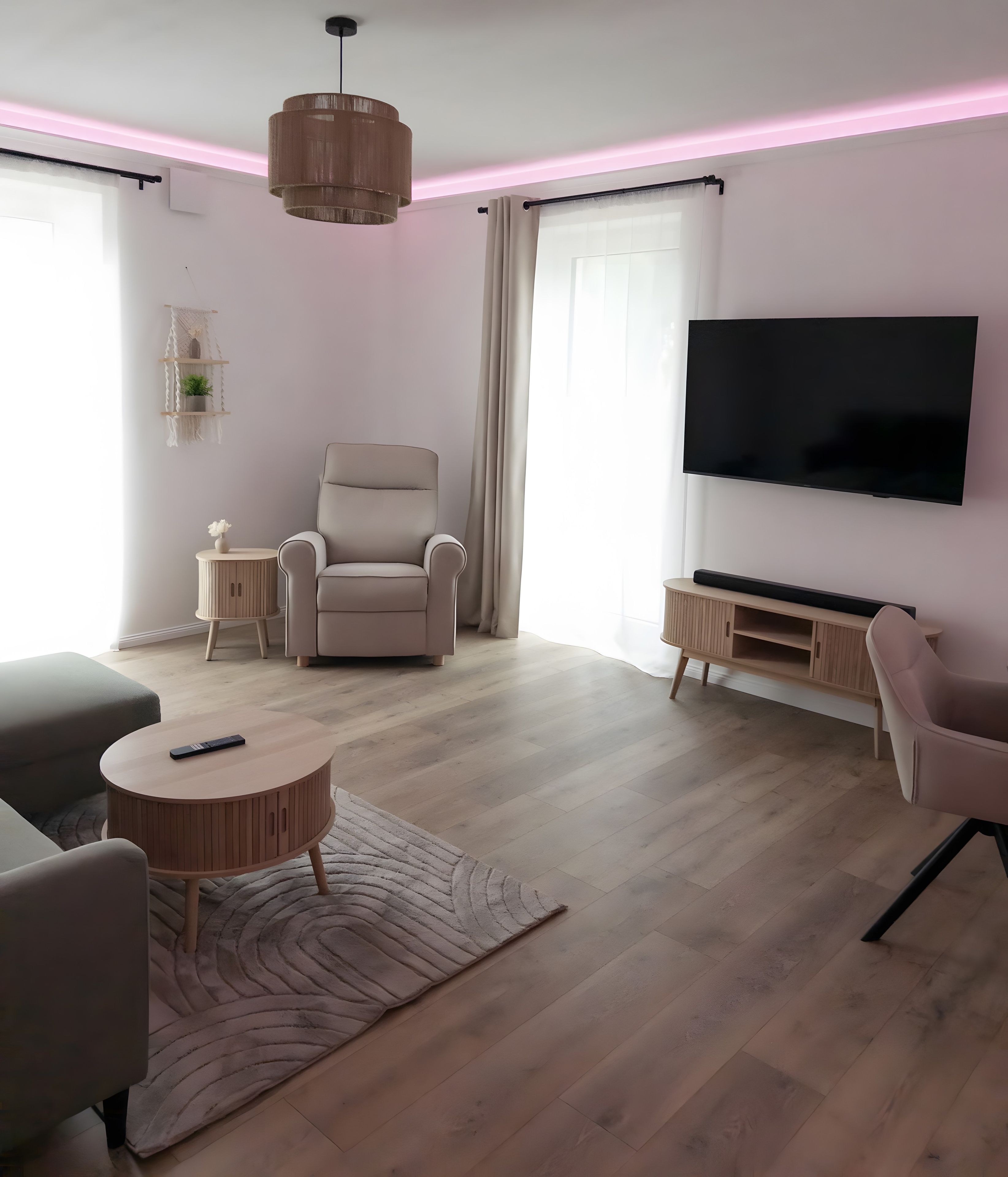 A modern living room with a sofa, armchair, TV, and a small table.