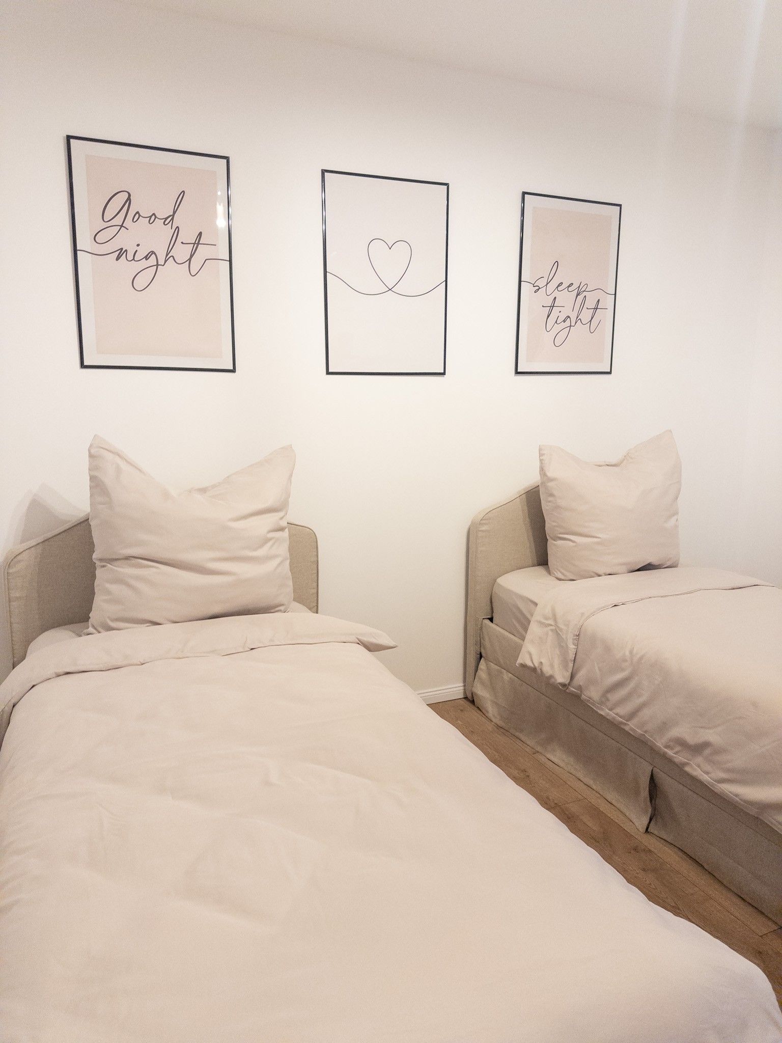 A bedroom with two beds, each with a pillow and a framed inspirational quote on the wall.