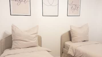 A bedroom with two beds, each with a pillow and a framed inspirational quote on the wall.