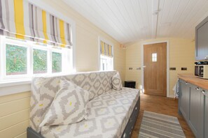 A cozy room with a sofa, a wooden door, and a kitchen area with a microwave. - Toast Stays - Elsie's Retreat (Durham)