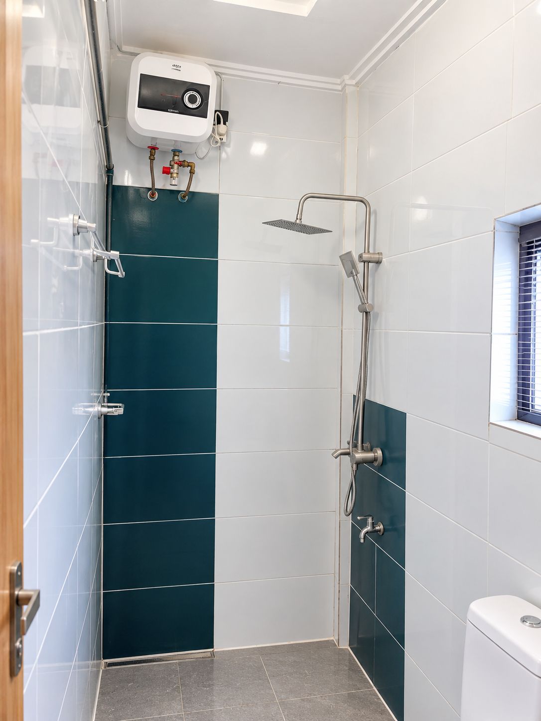 A modern bathroom with a shower, a toilet, and a control panel above the shower.