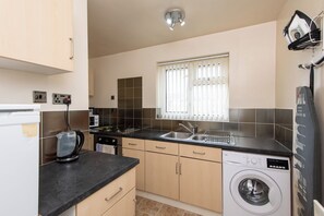 A compact kitchen with a washing machine, a kettle, and a sink. - Toast Stays - The Barden Residence (Darlington)