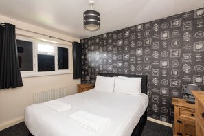 Ein Schlafzimmer mit einem Bett, einem Fenster, einer Heizung, einem Nachttisch und einer Wand mit motivierenden Zitaten.