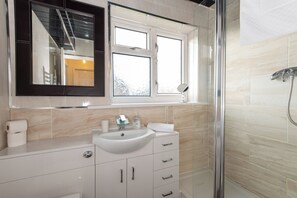 A modern bathroom with a white sink, mirror, and shower. - Toast Stays - The Barden Residence (Darlington)
