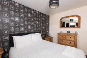 A bedroom with a bed, a dresser, a nightstand, a mirror, and a wall with motivational quotes. - Toast Stays - The Barden Residence (Darlington)