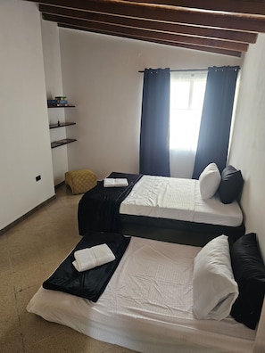 A room with two beds, a shelf with books, and a window with curtains. - New Listing (Medellín)