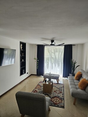 A living room with a sofa, armchair, coffee table, and a television mounted on the wall. - New Listing (Medellín)