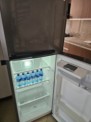 A refrigerator with a freezer compartment containing water bottles and a small freezer drawer. - New Listing (Medellín)