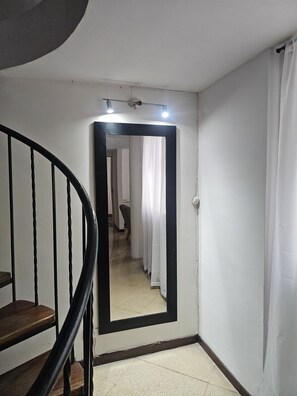 A hallway with a large mirror, a staircase, and a door leading to another room. - New Listing (Medellín)