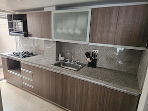 A kitchen with a granite countertop, stainless steel sink, wooden cabinets, and a built-in microwave. - New Listing (Medellín)