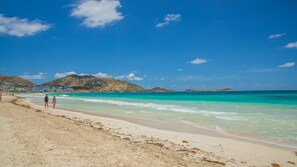 A beach with clear turquoise water, a sandy shore, and distant mountains. - New Listing (Saint-Martin)