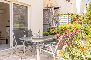 An outdoor patio with a glass table and chairs, a bottle of wine, and various plants. - Villa Lilly Rose - Three Bedroom Villa, Sleeps 6 (Polis)