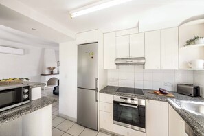 Una cocina moderna con armarios blancos, un refrigerador de acero inoxidable, horno empotrado y microondas.