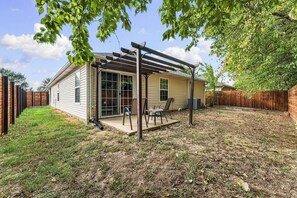 A house with a covered patio, a fenced backyard, and a wooden fence. - Riders Ready! Pet Friendly Downtown Bentonville/Momentary Location (Bentonville)