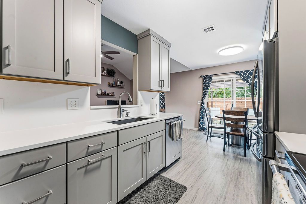 A modern kitchen with white cabinets, a sink, and a dining area with a table and chairs.